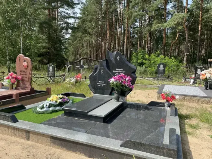 Двойной памятник фигурной формы из чёрного гранита с крестами и цветником