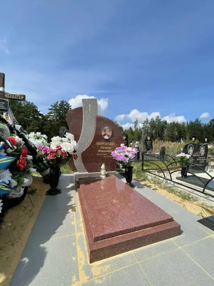 Памятник полукруглой формы из бордового гранита с крестом и овальным портретом